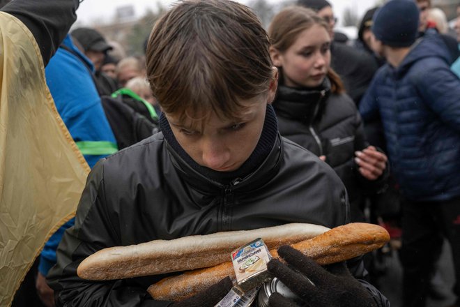 Deček drži v rokah hrano, ki jo je prejel v središču Hersona. Foto: Bulent Kilic/Afp
