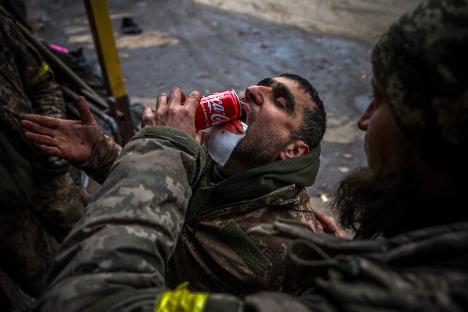 Ukrajinski vojak pomaga ranjenemu tovarišu piti med evakuacijo v&nbsp; mobilni bolnišnici v okolici Bakhmuta v regiji Doneck&nbsp; med rusko invazijo na Ukrajino. Foto: Anatolij Stepanov/Afp
