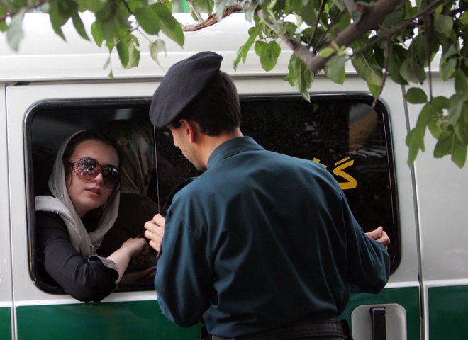 Pripadnik iranske moralne policije v akciji. Foto Behrouz Mehri/AFP
