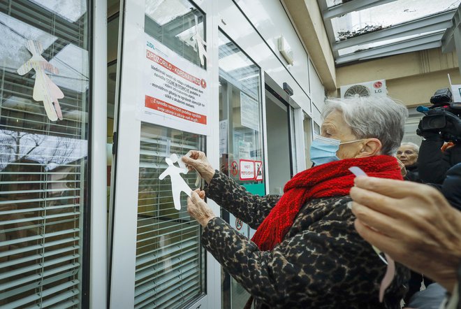 Lepljenje silhuet na vrata zdravstvenega doma. FOTO: Jože Suhadolnik/Delo
