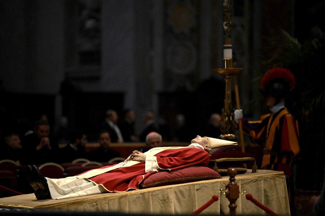 Posmrtni ostanki papeža Benedikta XVI. od včeraj ležijo v baziliki svetega Petra, kjer bo v četrtek vodil pogrebne slovesnosti njegov naslednik Frančišek. FOTO: Tiziana Fabi/AFP
