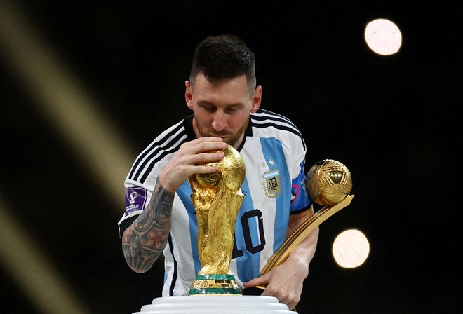 Lionel Messi je po zmagi v finalu SP poljubil pokal. FOTO: Kai Pfaffenbach/Reuters
