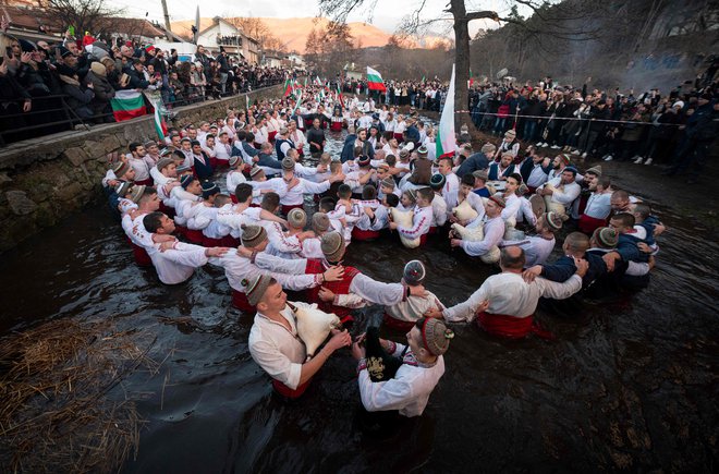 Bolgarski moški so danes zjutraj plesali tradicionalni ples &raquo;horo&laquo; v mrzli reki Tunjice v mestu Kalofer v okviru praznovanja pravoslavnega božiča. Po tradiciji pravoslavni duhovnik v reko vrže križ in verjame se, da bo tisti, ki ga dobi nazaj, vse leto zdrav, prav tako pa tudi vsi tisti, ki plešejo v ledenih vodah. Foto: Nikolay Doychinov/Afp
