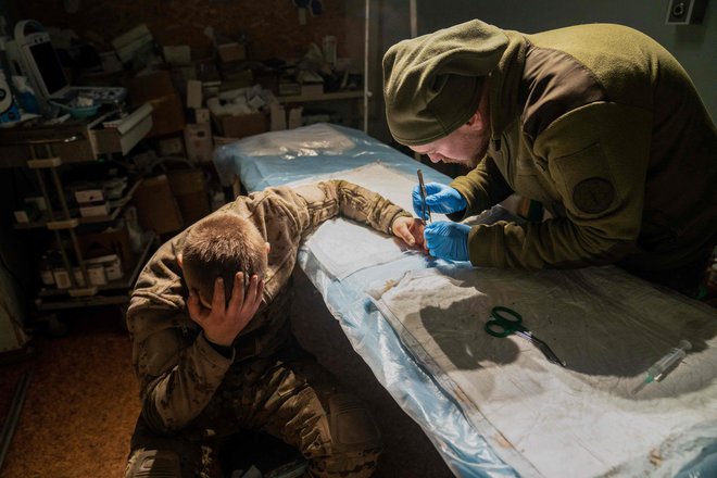 Vojaški zdravnik operira lažje ranjenega ukrajinskega vojaka v bolnišnici blizu frontne črte v regiji Doneck. Foto: Ihor Tkachov/Afp
