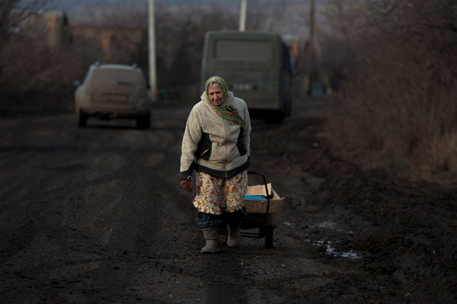 78-letnica iz regije Doneck s humanitarno pomočjo. FOTO: Stringer/Reuters
