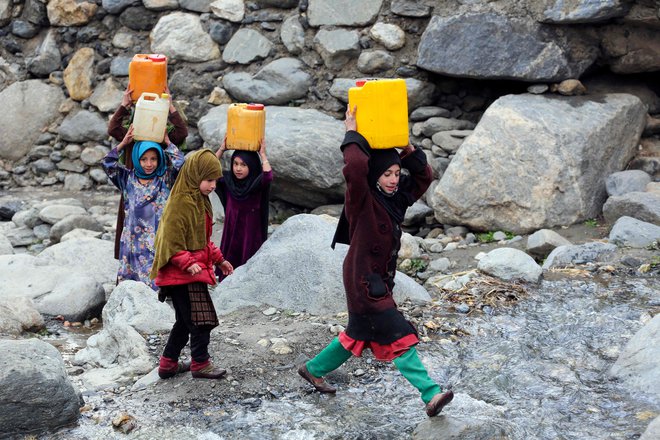 Afganistanska dekleta nosijo kanistre s pitno vodo, ki so jo napolnile iz potoka v okrožju Dara-i-Nur v provinci Nangarhar. Foto: Shafiullah Kakar/Afp
