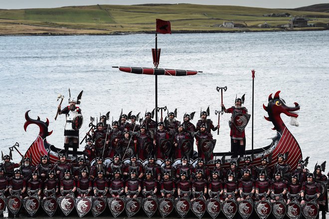 Člani skupine Jarl Squad pozirajo s svojo vikinško ladjo v Lerwicku na Šetlandskih otokih pred uradnim začetkom festivala &raquo;Up Helly Aa&laquo;. Up Helly Aa praznuje vpliv skandinavskih Vikingov na Šetlandskih otokih, vrhunec pa se zgodi, ko se stemni in 1000 &raquo;guizerjev&laquo; (moški v kostumih), meče goreče bakle v svoj vikinški čoln, ki ga na koncu zažgejo. Foto: Andy Buchanan/Afp

