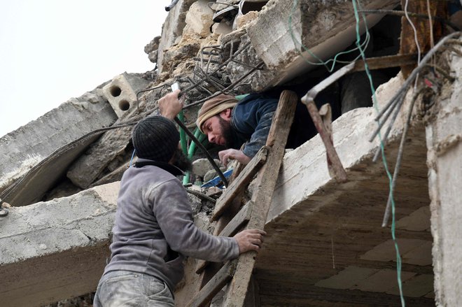 Poškodovanemu človeku pomaga stanovalec v Alepu v Siriji. FOTO: Rami Al Sayed/AFP
