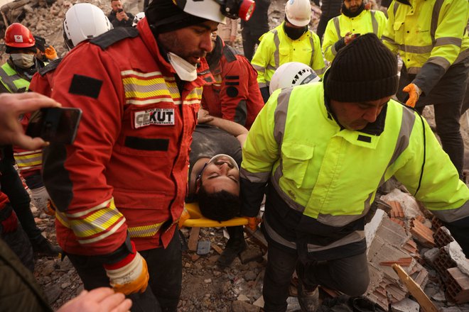 Reševalci pomagajo 30-letnemu preživelemu. FOTO: Stoyan Nenov/Reuters
