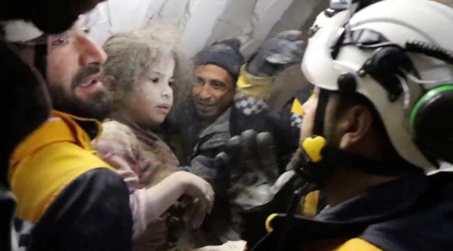 Pripadniki Belih čelad, ki so izpod ruševin rešili otroka v Jandarisu v Siriji. FOTO: White Helmets/Reuters
