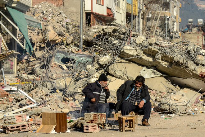 Sorodniki žrtev ob uničeni stavbi v Adiyamanu v Turčiji. FOTO: Ilyas Akengin/AFP
