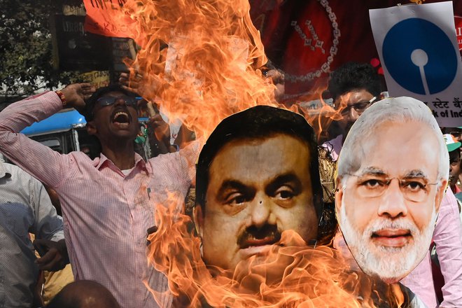 Protestno zažiganje podob predsednika vlade Narendre Modija in indijskega tajkuna Gautama Adanija na shodu proti finančni politiki vlade v Kalkuti. FOTO: Dibyangshu Sarkar/AFP
