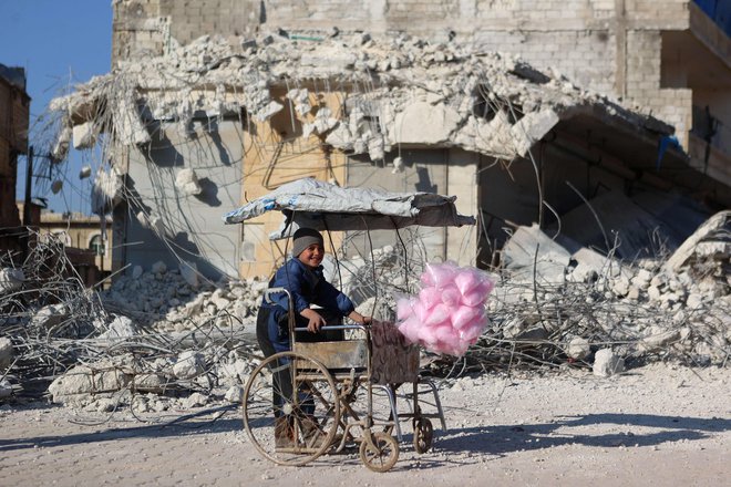 Sirski deček prodaja sladkorno vato pred ruševinami stavbe, ki se je zrušila po potresu prejšnji teden v sirski vasi Atarib v severozahodni provinci Alep, ki je pod nadzorom upornikov. V potresu, ki je 6. februarja opustošil območja Sirije in sosednje Turčije, je umrlo več kot 40.000 ljudi, od tega najmanj 3.600 v Siriji. Foto: Aaref Watad/Afp
