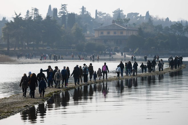 Gardsko jezero ima najnižjo zimsko gladino v 35 letih, kar so izkoristili številni sprehajalci. FOTO: Piero Cruciatti/AFP
