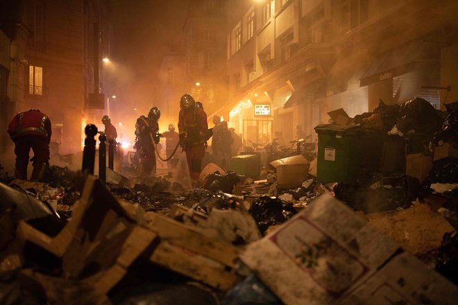 V Parizu gasilci preverjajo smeti po gašenju požara med demonstracijami teden dni po tem, ko je vlada z uporabo tretjega odstavka 49. člena ustave 23. marca 2023 v parlamentu brez glasovanja spravila v veljavo pokojninsko reformo. Včeraj se je v Franciji več kot milijon protestnikov udeležilo demonstracij proti pokojninski reformi predsednika Emmanuela Macrona, samo v Parizu jih je bilo na ulicah več kot 120.000. Foto: Anna Kurth/Afp
