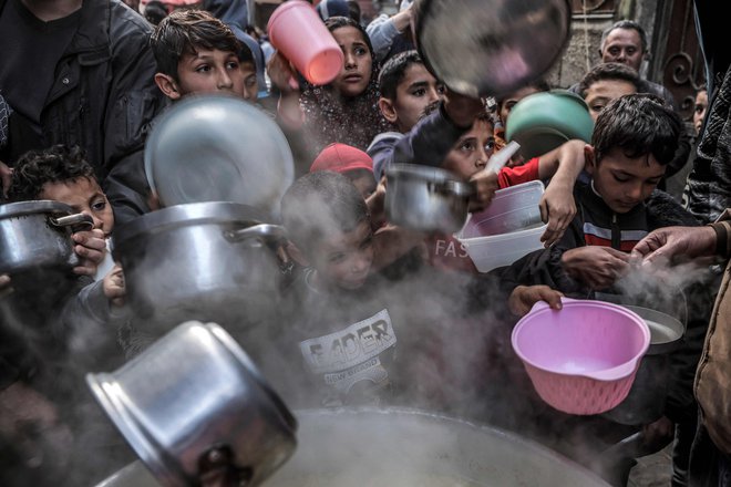 Na ulici v Gazi otroci držijo lonce in posode za juho, ki jo je pripravil Palestinec Walid al-Hattab, med postom na drugi dan muslimanskega svetega meseca ramadan. Foto: Mohammed Abed/Afp
