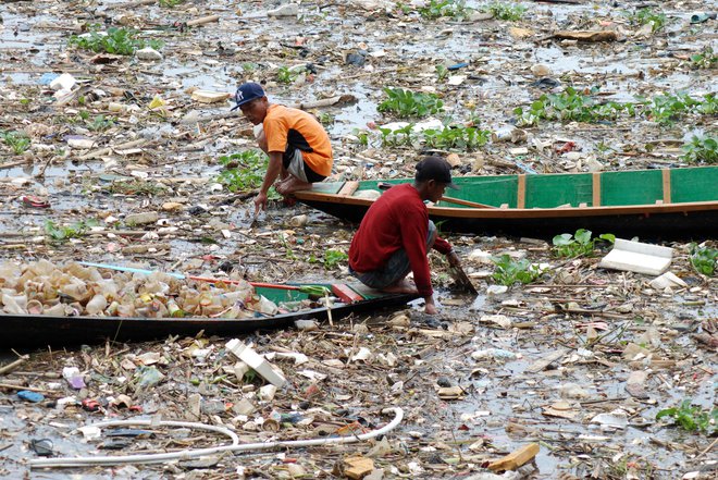 Smetarja na čolnih zbirata plastiko v izredno onesnaženi reki Citarum v Bandungu na zahodu indonezijskega otoka Java. Foto: Timur Matahari/Afp