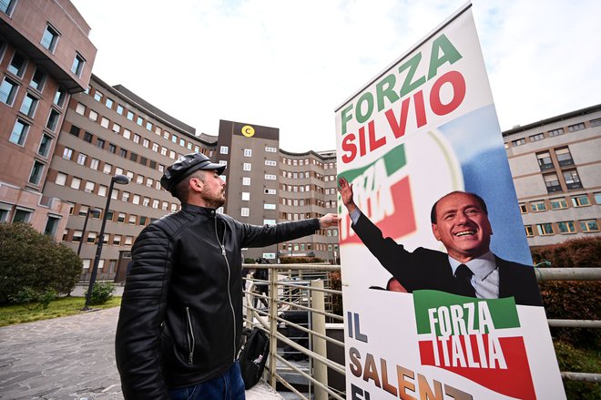 Privrženec ostarelega italijanskega politika je pred poslopjem milanske bolnišnice San Raffaele razprostrl transparent z napisom »Naprej, Silvio«. FOTO: Piero Cruciatti/AFP