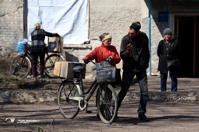 Prebivalci prihajajo po humanitarno pomoč v okolici Bahmuta, kjer potekajo hudi boji. FOTO: Kai Pfaffenbach/Reuters