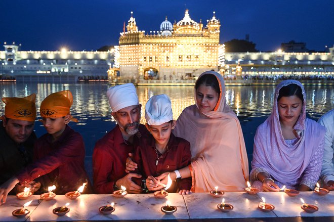 Sikhovski verniki prižigajo sveče pred osvetljenim Zlatim templjem ob obletnici rojstva devetega sikhovskega guruja Teg Bahadurja v Amritsarju. Foto: Narinder Nanu/Afp