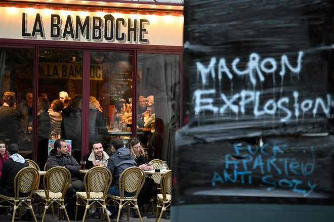 Obiskovalci ene od kavarn na zahodu Francije. Zraven na pročelju napis »Macronova eksplozija«. FOTO: Damien Meyer/Afp