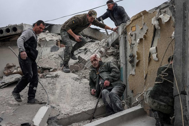 Reševalci se skušajo prebiti do starejšega moškega, ranjenega v ruskem napadu na Slovjansk. FOTO: Anatolii Stepanov/Afp