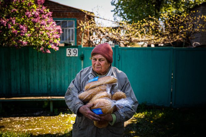 Ukrajinka drži kruh iz humanitarne pomoči pred svojo hišo v Siversku v regiji Doneck med rusko invazijo na Ukrajino. Foto: Dimitar Dilkoff/Afp