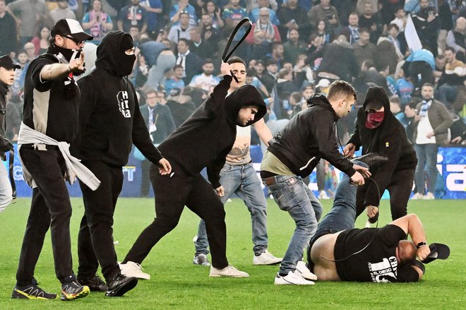 Navijači Udineseja so napadli navijača Napolija po koncu tekme, ko so gledalci vdrli na igrišče. Nogometna tekma se je v Vidmu končala brez zmagovalca. Napoli je 4. maja končal 33-letno čakanje na zmago v italijanski serie A, potem ko si je z remijem 1:1 zagotovil tretji naslov prvaka. Foto: Tiziana Fabi/Afp