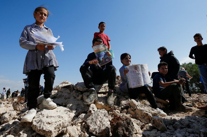 Palestinski šolarji z poškodovanimi učbeniki po izraelskem rušenju šole. FOTO: Mussa Issa Qawasma/Reuters