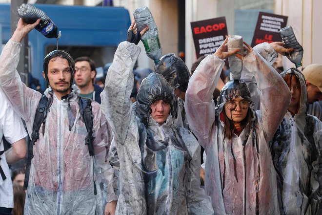 Protestniki proti podnebnim spremembam so se polili z oljem med demonstracijami na obrobju pariškega prizorišča letne skupščine naftne družbe TotalEnergies v Parizu. Prišlo je tudi do spopadov med policijo in protestniki, pri katerih je bil uporabljen solzivec. Francoski naftni in plinski velikan je tarča koalicije združenj, ki grozijo, da bodo blokirala skupščino, pa tudi nekateri njegovi delničarji se ne strinjajo s podnebno politiko družbe. Foto: Geoffroy Van Der Hasselt/Afp