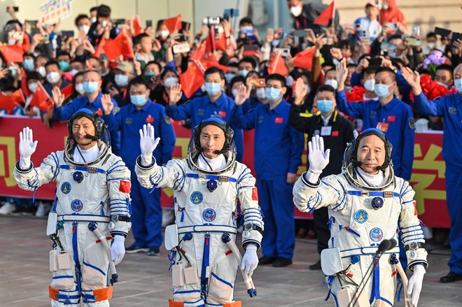 Od leve: Gui Haichao, Zhu Yangzhu in Jing Haipeng mahajo navdušeni množici, ki je spremljala izstrelitev posadke proti vesoljski postaji. FOTO: Hector Retamal/AFP