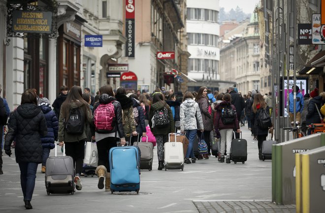 Turisti Ljubljanico, Tromostovje, Križanke in NUK vidijo skozi kamere svojih mobilnih telefonov. FOTO: Matej Družnik/Delo