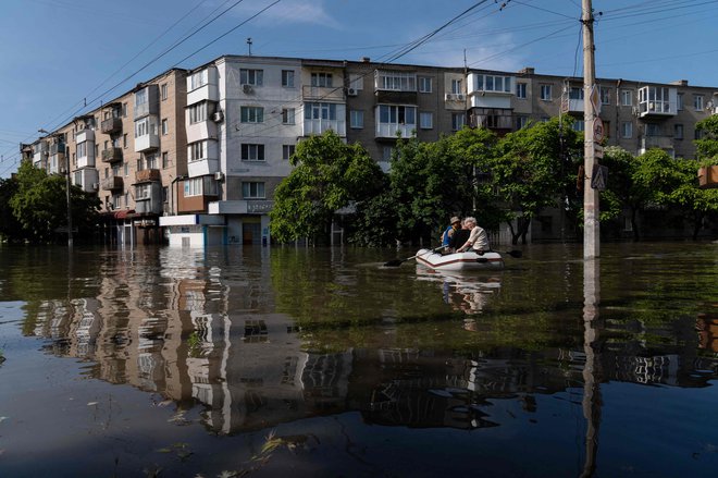 Ukrajinske varnostne sile prevažajo lokalne prebivalce v čolnu med evakuacijo s poplavljenega območja v Hersonu. FOTO: Aleksey Filippov/AFP