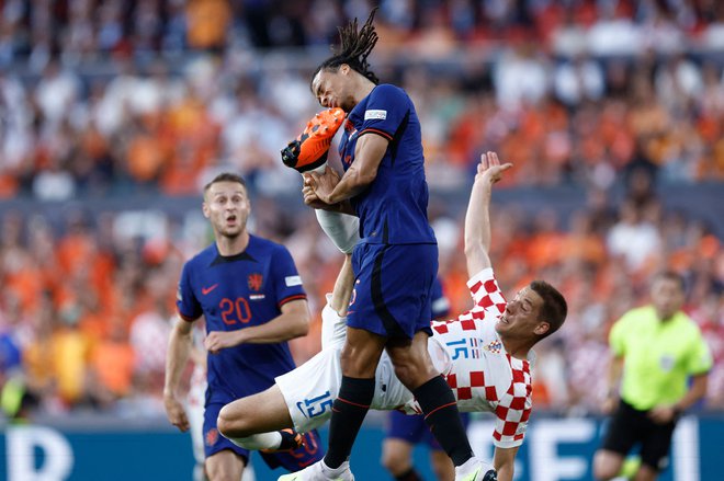 Hrvaški vezist Mario Pašalić je brcnil nizozemskega branilca Nathana Akeja, ki je poskuša zadeti žogo na polfinalni nogometni tekmi Lige narodov med Nizozemsko in Hrvaško v Rotterdamu. Hrvati so po podaljšku premagali Nizozemce s 4:2. Foto: Kenzo Tribouillard/Afp