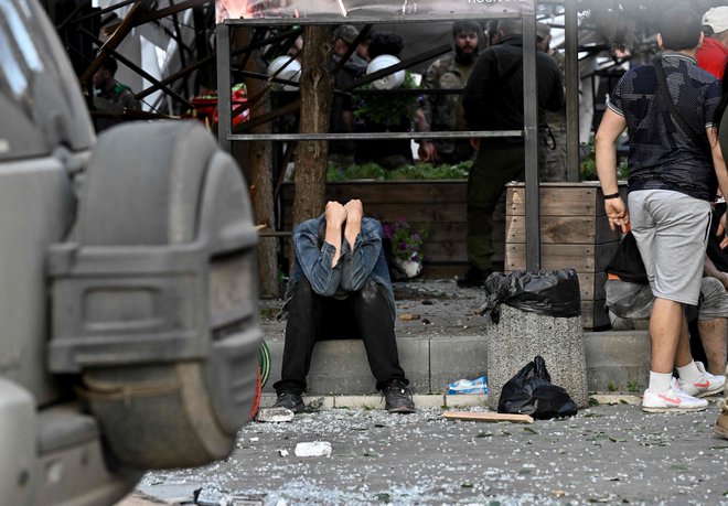 Moški pred poškodovano stavbo v Kramatorsku. FOTO: Genya Savilov/AFP