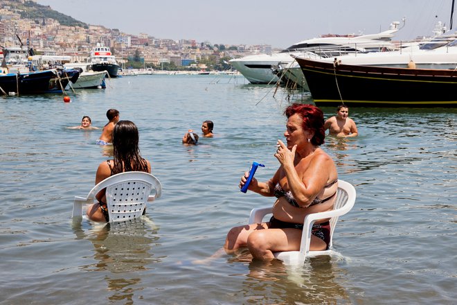 Ženska se hladi v morju v Neaplju med vročinskim valom, ki je zajel večji del Evrope. Foto: Ciro De Luca/Reuters