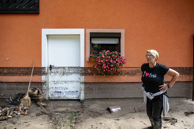 Županja Romana Lesjak v Žerjavu kaže, do kam je segala voda na eni od prizadetih stanovanjskih hiš. FOTO: Voranc Vogel/Delo