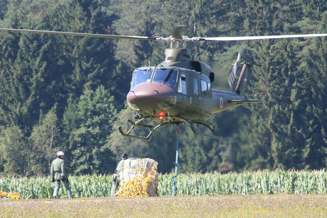 Pripenjanje tovora na letališču poteka med lebdenjem helikopterja, enako tudi raztovarjanje na terenu. Foto Borut Podgoršek