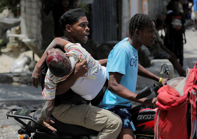 Ljudje peljejo ranjenega mladeniča v bolnišnico, potem ko so tolpe zavzele njihovo sosesko Carrefour Feuilles v Port-au-Princeu na Haitiju, kjer se poleg vse večjega nasilja soočajo še z izbruhom kolere. Za vzpostavitev reda in miru na Haitiju je potrebna uporaba močne sile večnacionalne policijske napotitve, ki bi bila sposobna tudi razorožiti tolpe, je dejal generalni sekretar ZN-a Antonio Guterres v poročilu Varnostnemu svetu. Foto: Ralph Tedy Erol/Reuters