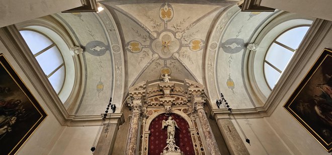 Oltar s kamnitim okvirjem za sliko Marija s pasom in štukatura na stropu. Foto Boris Šuligoj