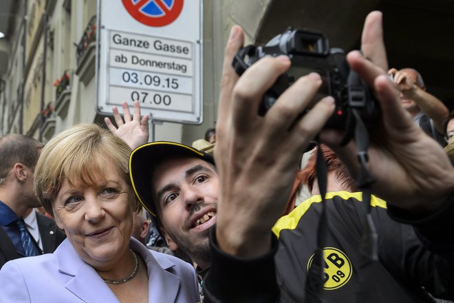 Nekdanja kanclerka Angela Merkel med fotografiranjem z begunci FOTO: Fabrice Coffrini/AFP