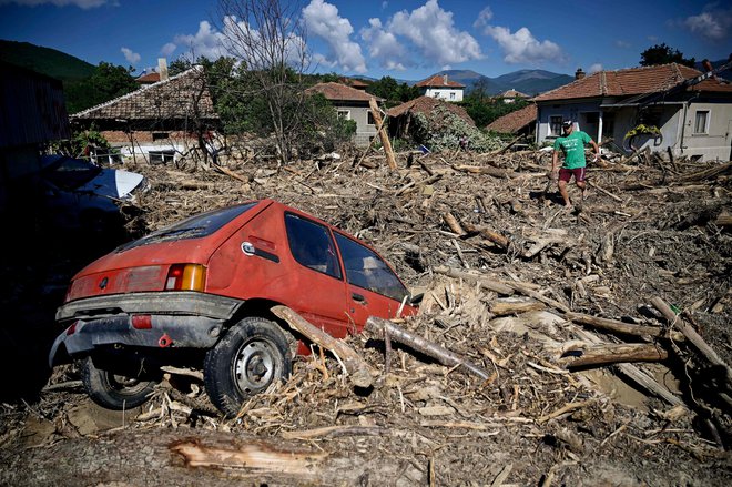 Avto med naplavinami na glavni cesti skozi vas Slatina v notranjosti Bolgarije pred letom. FOTO: Nikolay Doychinov /AFP