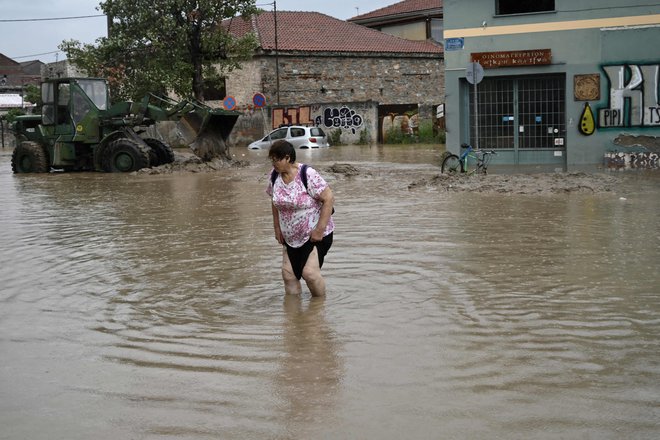 Prebivalec Volosa brodi po narasli vodi. FOTO: Sakis Mitrolidis/Afp