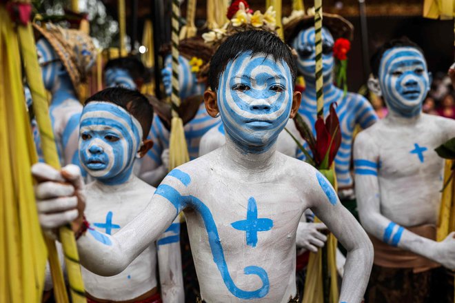 Fantje, pobarvani kot strašljiva mitska bitja, ki simbolizirajo ravnovesje med temo in svetlobo, v Tegalalangu na Baliju čakajo, da bodo izvedli svoj tradicionalni hindujski obred »ngerebeg«, s katerim si prizadevajo za boljše življenje z nevtralizacijo negativnih vplivov na ljudi in vesolje. Foto: Garry Lotulung/Afp