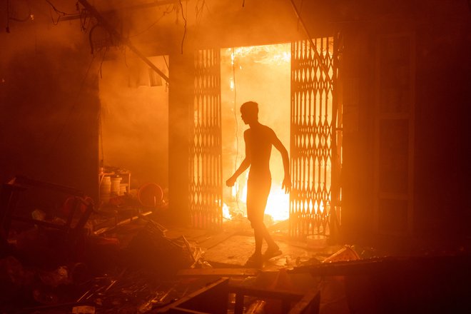 Oseba stoji v goreči stavbi med požarom ki je izbruhnil na tržnici v Daki. Foto: Arshadul Hoque Rocky Arshadul Hoque/Reuters
