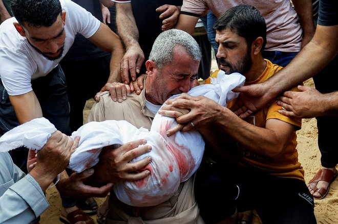 Žalujoči med pokopom trupla palestinskega otroka, ki je bil ubit v izraelskih napadih na južnem območju Gaze. FOTO: Ibrahim Abu Mustafa/Reuters