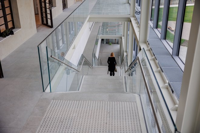 Vzdolž severne fasade stare tovarne se razteza stekleni prizidek, ki ga zaznamuje monumentalno betonsko stopnišče. FOTO: Črt Piksi