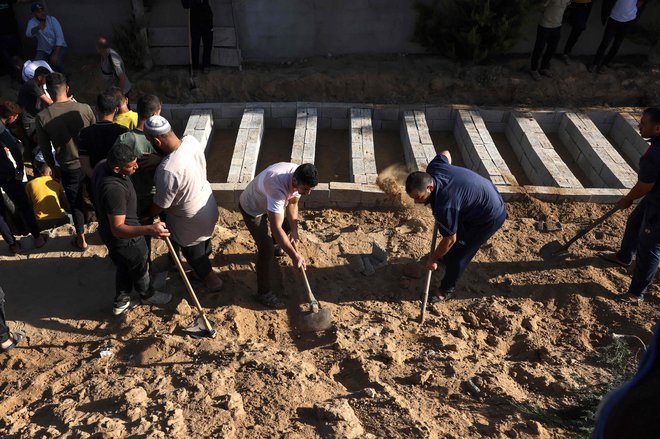 Ljudje kopljejo nove grobove v Gazi. FOTO: Mohammed Abed/AFP
