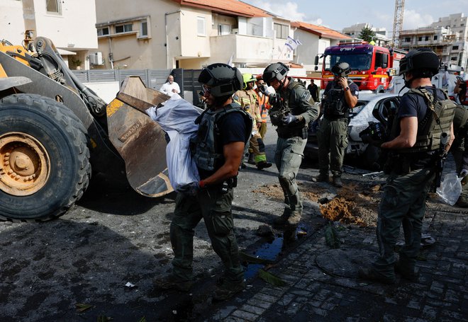 Odstranjevanje ostankov rakete, ki je priletela iz Gaze. FOTO: Amir Cohen/Reuters