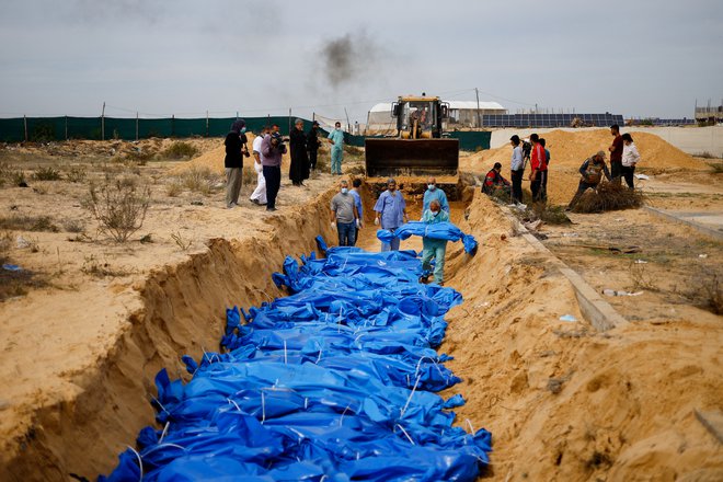 Trupla Palestincev, ubitih med izraelskim obstreljevanjem Gaze, so danes zakopali v množičen grob v Kan Junisu na jugu enklave. FOTO: Mohammed Salem/Reuters